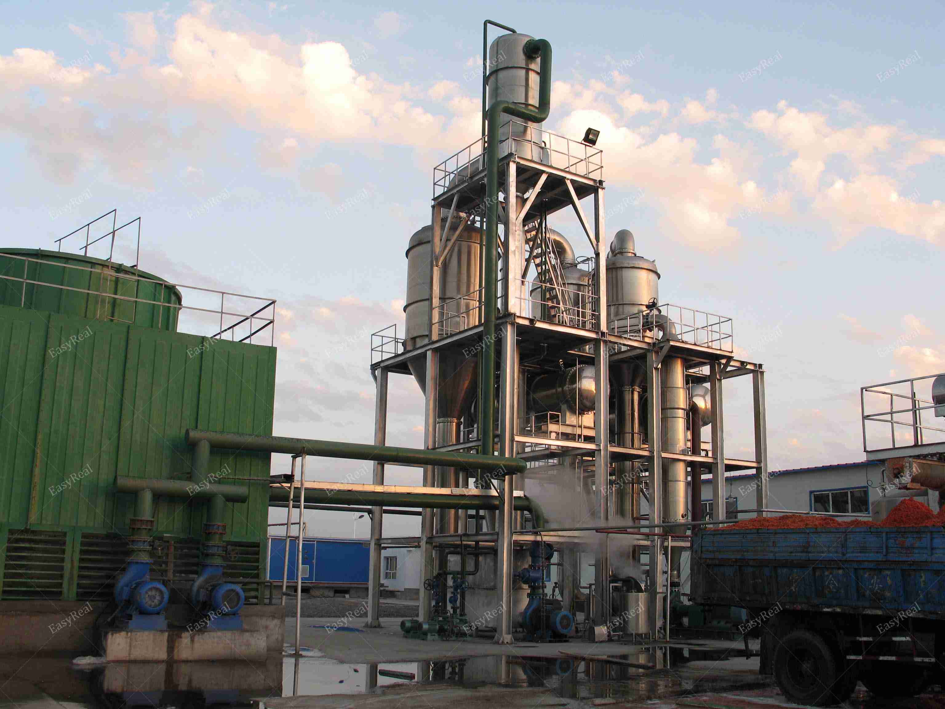 Outdoor view of EasyReal multi-effect forced circulation evaporator with vertical vessels, recirculation pumps and piping installed in a tomato paste and fruit puree concentration plant.