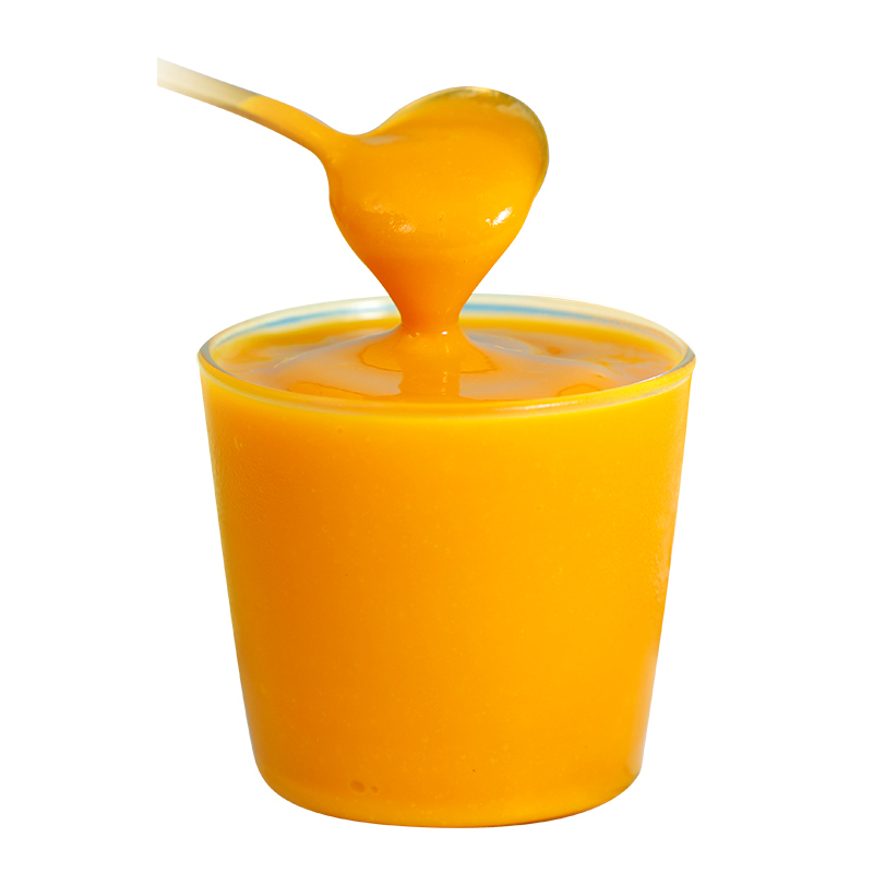 Fresh mango puree in transparent plastic cup, smooth texture and bright yellow color, final product of industrial mango pulp processing line.