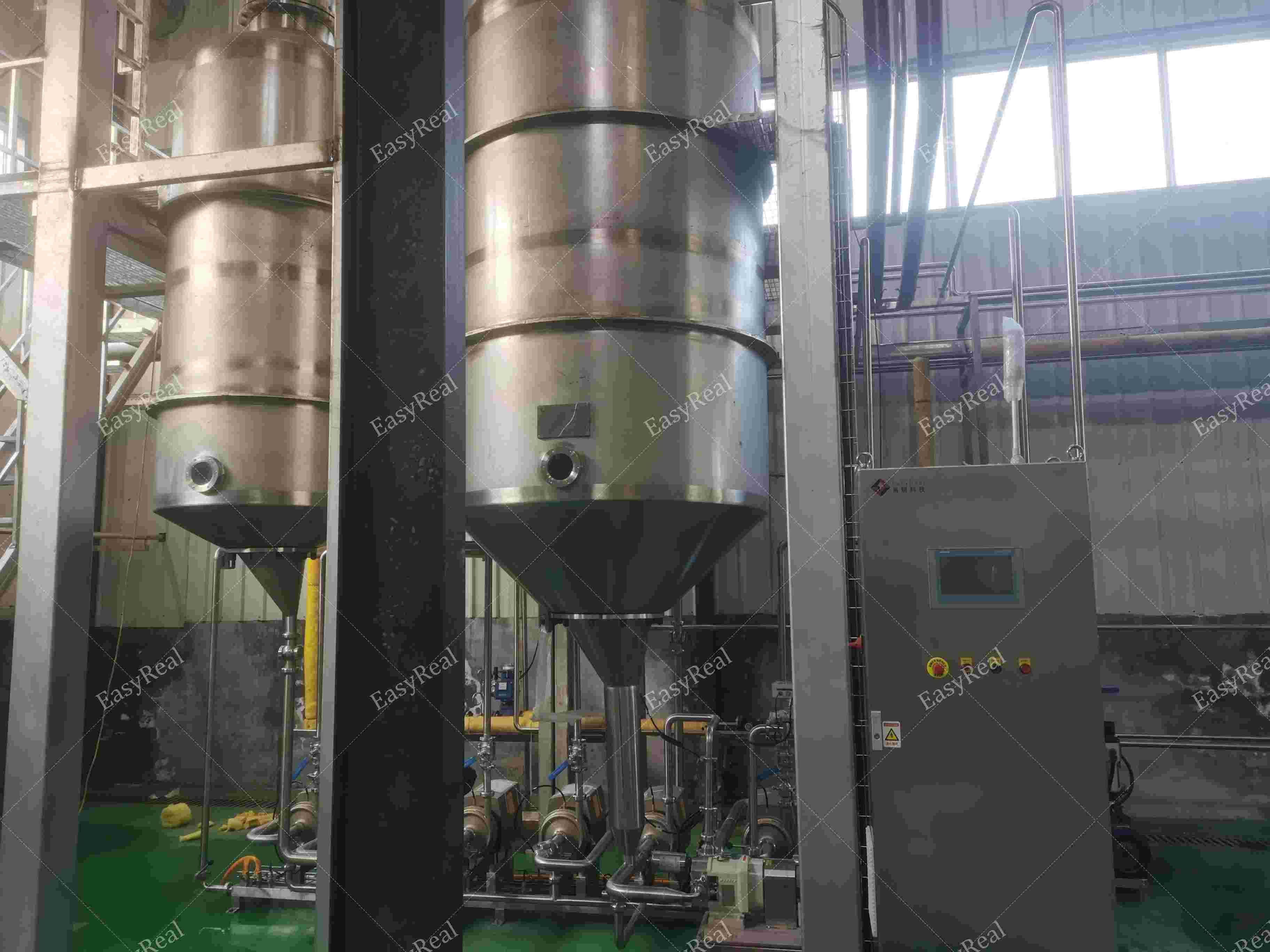 Stainless steel falling film evaporator with circulation pumps and piping installed in EasyReal fruit and tomato juice concentration line.