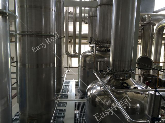 Close-up view of EasyReal stainless steel falling film evaporator columns, platforms and process piping inside the juice concentration plant.