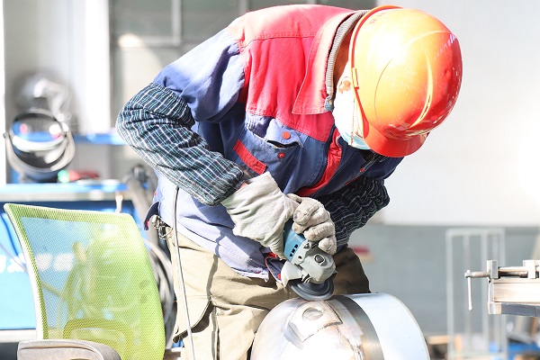 Technician welding and polishing stainless-steel tank components in EasyReal workshop, ensuring high hygiene standards for food processing equipment.